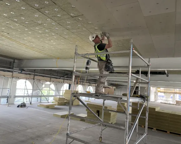 Plasterer working from a scaffold tower on an open-plan commercial floor