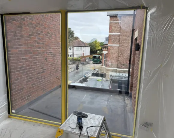 Window opening masked with protective sheeting ready for glass polishing on a construction site