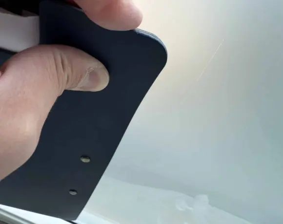 Hand holding a polishing tool against the edge of a glass panel