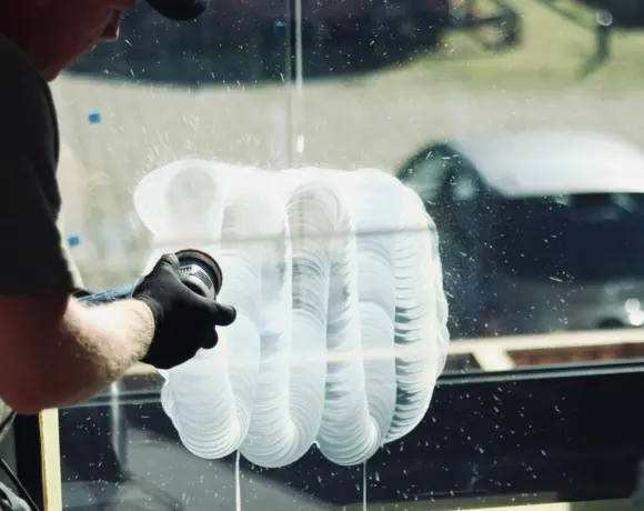 Gloved technician polishing a window pane with a rotary polisher