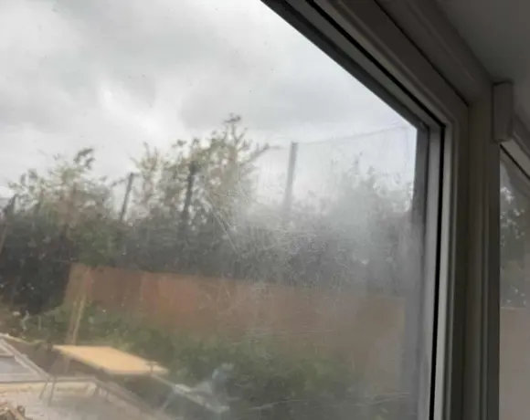 Hazy scratched window glass before polishing, looking out onto a garden